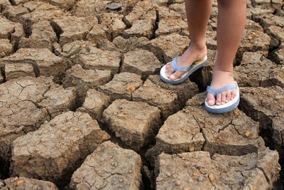 Low section of child standing on drought land