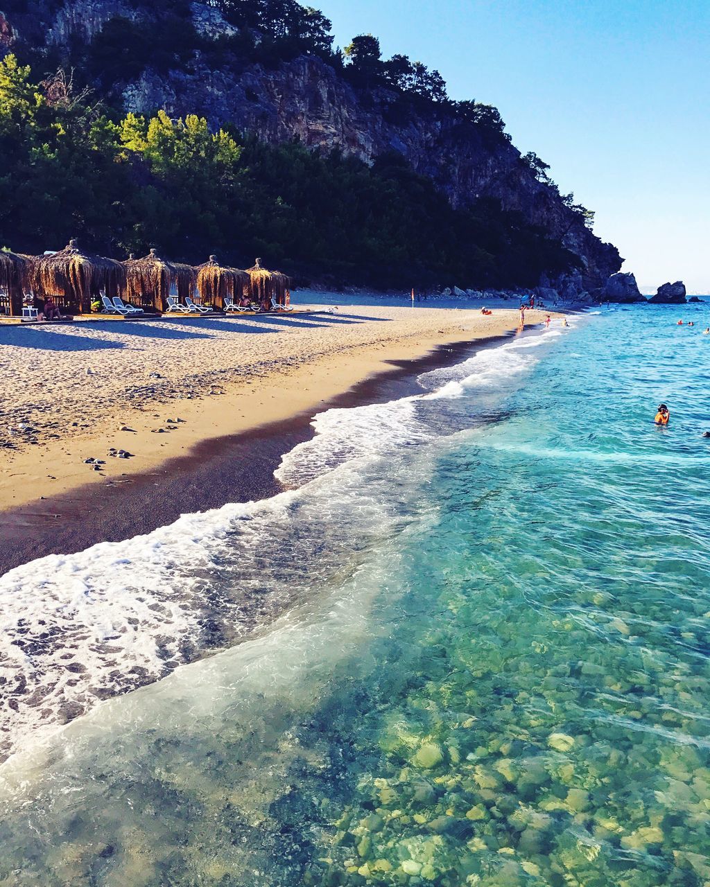 water, nature, beauty in nature, sea, beach, scenics, tranquility, rock - object, day, tranquil scene, outdoors, sand, sky, vacations, tree, no people, travel destinations, mountain, clear sky, animal themes