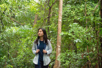 Young woman looking away while hiking in forest
