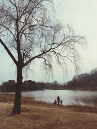 People standing by lake against sky