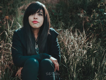 Portrait of young woman sitting on field