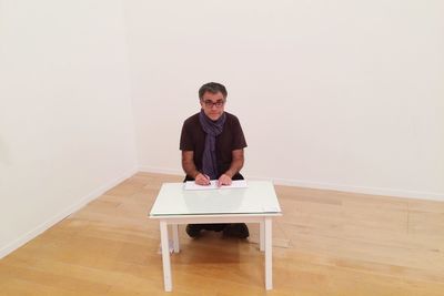 Portrait of young man sitting on table at home
