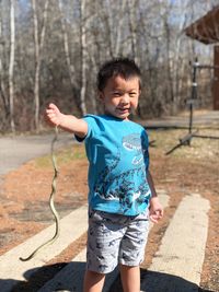Smiling kid holding snake while standing at park