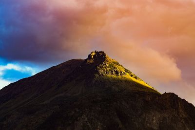 Low angle view of rocks on mountain against sky during sunset