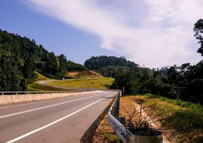 Road by trees against sky