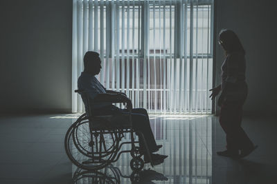 Woman by man sitting on wheelchair