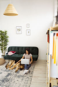 Full length portrait of woman sitting at home