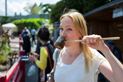 Portrait of young woman with long hair drinking from bamboo dipper