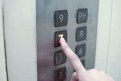 Close-up of hand pressing button in elevator