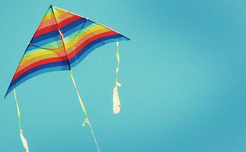 Low angle view of multi colored umbrella against clear blue sky