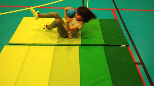 High angle view of girl playing on exercise mat in court