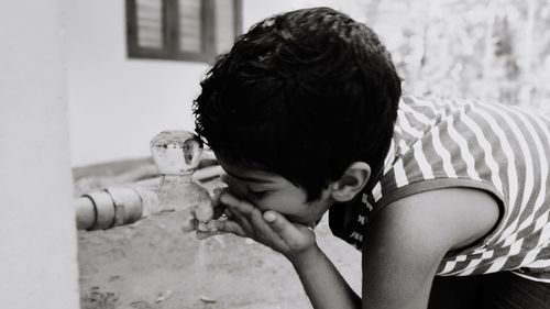 Boy drinking water from faucet