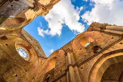 Low angle view of old ruin building against cloudy sky