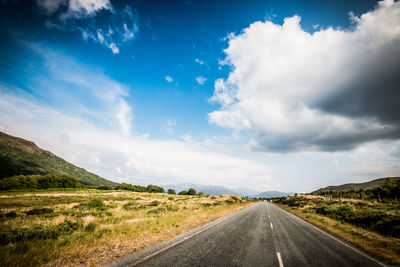 Empty road along landscape against sky