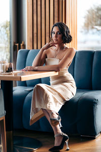 Young woman sitting on sofa at home