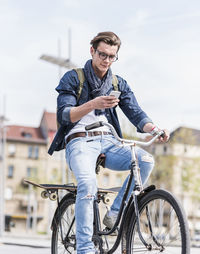 Young man with bicycle in the city using cell phone