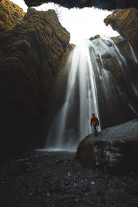 Full length of man standing against waterfall in cave
