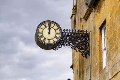 Low angle view of clock on wall against building