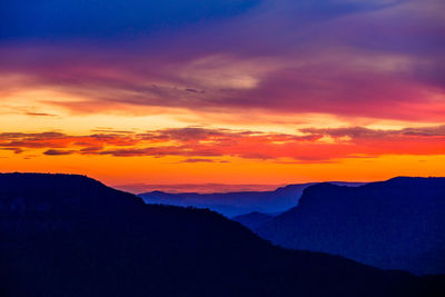 Scenic view of silhouette mountains against romantic sky at sunset