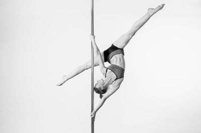 Low angle view of man hanging on pole against white background