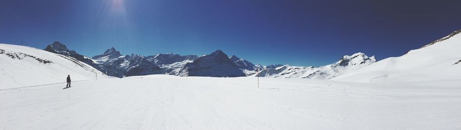 Scenic view of snow covered mountains against clear blue sky