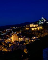 Illuminated cityscape against clear blue sky at night