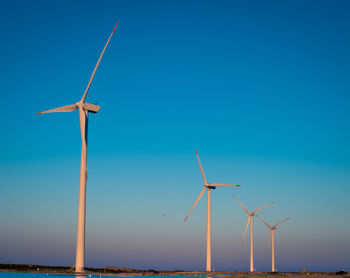 Low angle view of wind turbines against sky