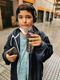 Portrait of boy holding camera while standing outdoors