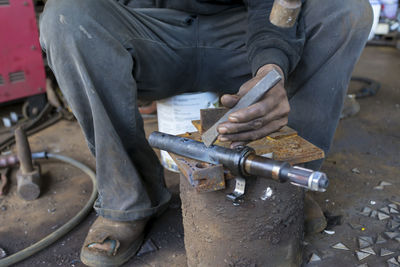 Low section of man working on metal