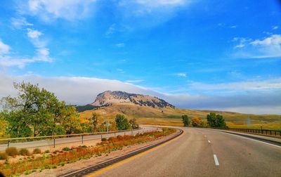 Road by landscape against blue sky