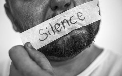 Close-up of man with text on adhesive tape stuck on lips