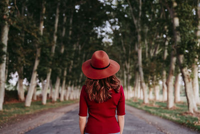 Rear view of woman standing amidst trees on road