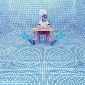 Low section of boy sitting in swimming pool