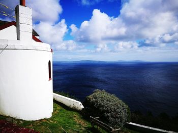 Lighthouse by sea against sky