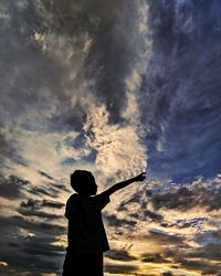 Rear view of silhouette boy standing against sky