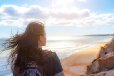 Woman standing at beach against sky