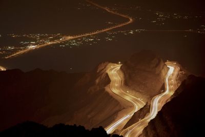 Aerial view of illuminated mountain road against sky at night