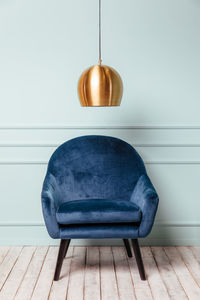 Blue armchair on turquoise background with a golden lamp