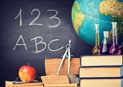 Close-up of educational materials on stacked books against blackboard