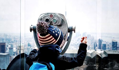 Tourist watching cityscape through coin-operated binoculars