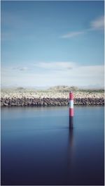Lighthouse by sea against blue sky