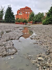 Reflection of building in puddle against sky