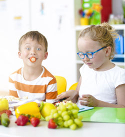 Children eating food while sitting on table at school