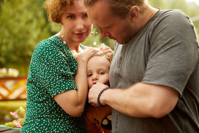 Family cuddling son in countryside green trees