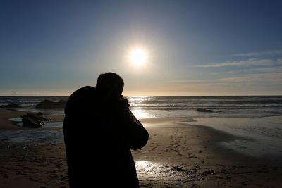 Silhouette man on beach against sky during sunset