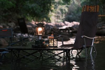 Camping in forest fo illuminated lantern on table