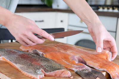 Female hands cutting fillet of red fish. red caviar. removing fish bones. butchering red fish meat.