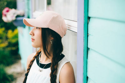 Thoughtful woman wearing cap by wall