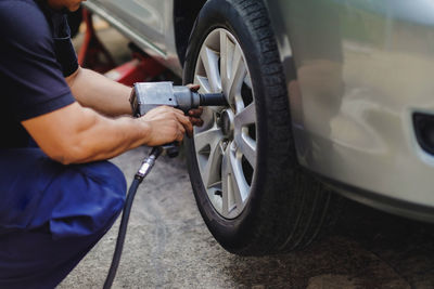 Midsection of mechanic changing car tire