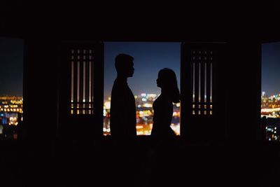 Silhouette people standing against illuminated building at night